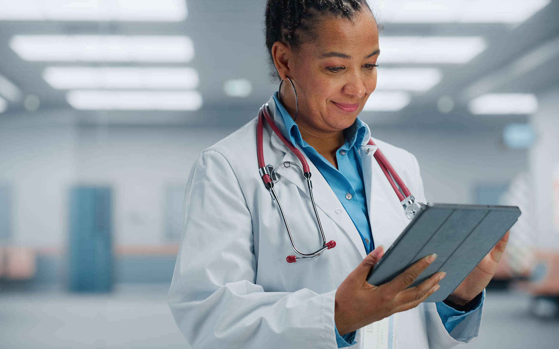 Confident African American female doctor looking at the tablet.