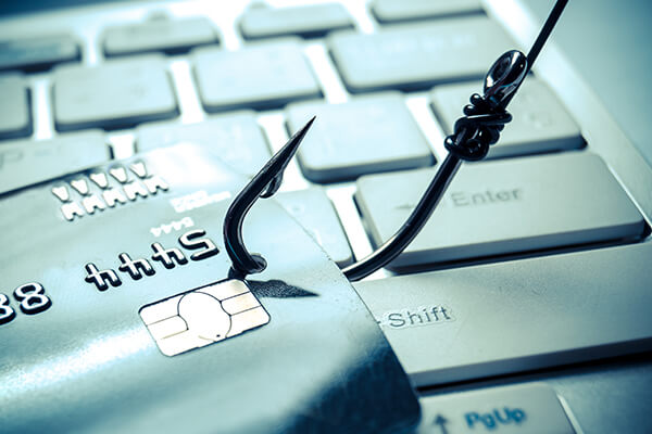 Credit card with fishing hook in it lying on a keyboard highlights the prevalence of online phishing scams