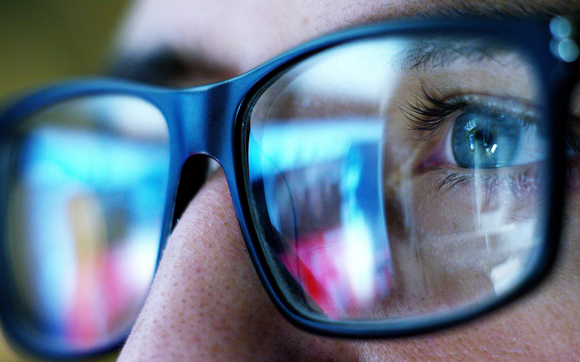 Closeup of a man with glasses looking at screen.