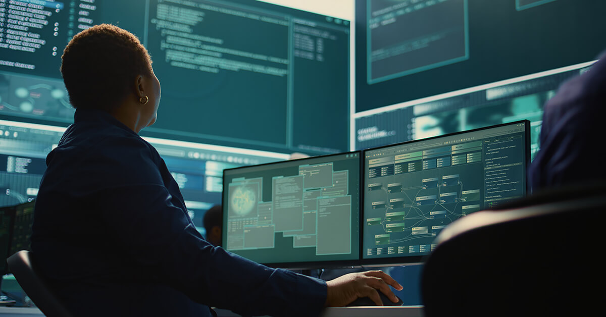 Cybersecurity professional monitoring systems across multiple screens.