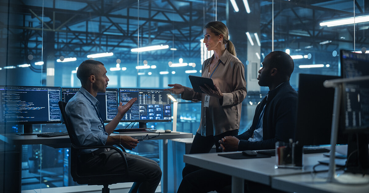 Cybersecurity professionals discussing system activity in a security operations center.