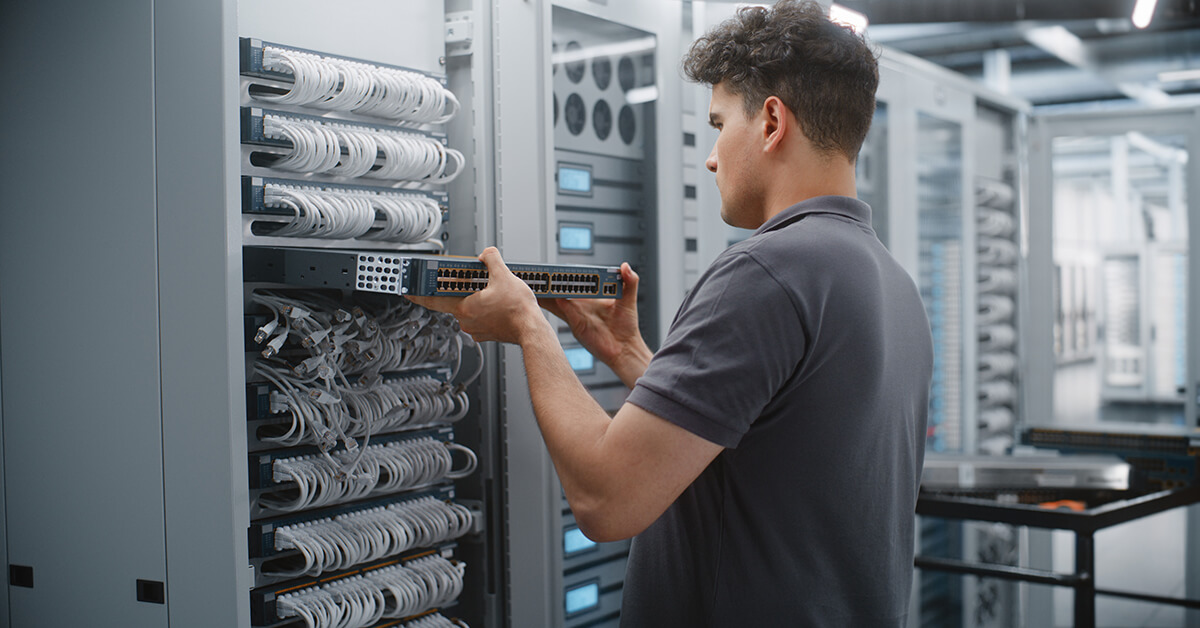 IT technician installing network equipment in a server rack.